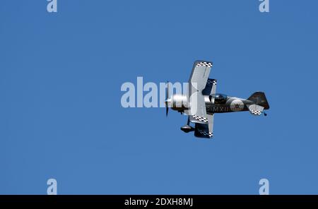 Pitts Model 12  stunt byplane  with smoke trail and blue sky. Stock Photo