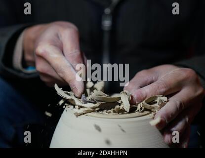 Jingdezhen, China's Jiangxi Province. 23rd Dec, 2020. A staff member of Kuaixueshiqing, a handicraft porcelain making team, trims an unburnt product in Jingdezhen, east China's Jiangxi Province, Dec. 23, 2020. The Kuaixueshiqing team based in Jingdezhen, known as China's porcelain capital, produces porcelain bowls and cups by combining multiple techniques. The team has more than 10 varieties of products, favored by both domestic and foreign consumers. Credit: Hu Chenhuan/Xinhua/Alamy Live News Stock Photo