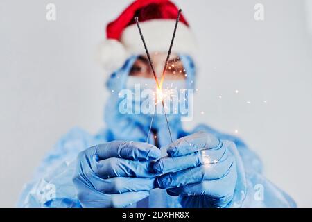 A nurse holds Christmas ornaments. A coronavirus hospital worker in protective workwear. Celebrating Christmas in hospital. Doctor celebrate New Year Stock Photo