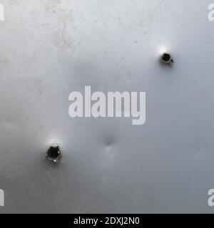 two bullet ragged hole in sheet metal wall or door Stock Photo