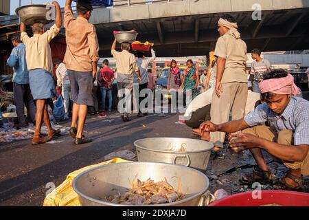 A small-time seafood vendor sorting shrimp at an open-air fish market, among brisk market activity; near Crawford Market in Mumbai, India Stock Photo