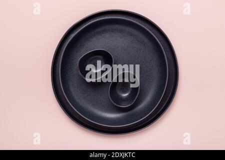Set of black ceramic plates and gravy boats on pink background. Top view - Image Stock Photo