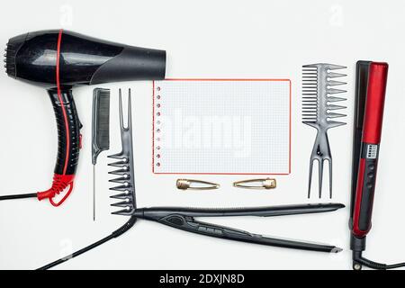 Working table of hairdresser with accessories and notepad on white. Females hairstylist workspace with hair cutting tools - combs, hair iron Stock Photo