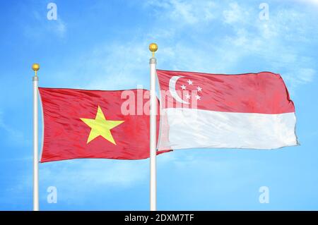 Vietnam and Singapore two flags on flagpoles and blue sky Stock Photo