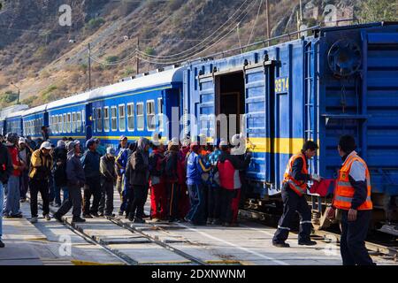 Aguas Calientes, Peru - June 24, 2015:  Workers load onto a freight car on a Peru Rail train at the Aguas Calientes stop near Macho Picchu. Stock Photo