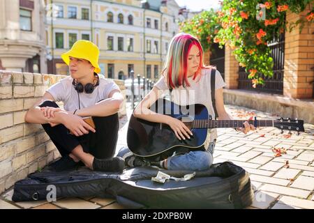 Couple of teenage hipsters street musicians making money by music