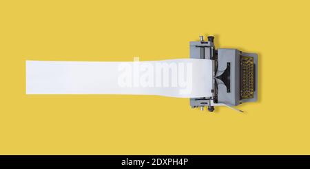 old typewriter with very long paper and yellow background with space for text Stock Photo