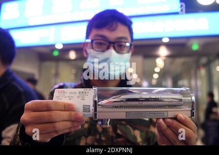 (201224) -- CHONGQING, Dec. 24, 2020 (Xinhua) -- A passenger shows a model of the Fuxing high-speed train and a train ticket for Chengdu East Railway Station in southwest China's Sichuan Province, at Shapingba Railway Station in southwest China's Chongqing on Dec. 24, 2020.  On Thursday morning, with G8608 and G8607 trains respectively pulling out of Chongqing Shapingba Railway Station and Chengdu East Railway Station, the Fuxing CR400AF trains plying on the railway linking Chengdu, capital of Sichuan Province, and Chongqing Municipality were officially put into operation at a speed of 350 km/ Stock Photo