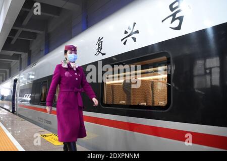 (201224) -- CHONGQING, Dec. 24, 2020 (Xinhua) -- A staff member walks past a high-speed train bound for Chengdu East Railway Station in southwest China's Sichuan Province, at Shapingba Railway Station in southwest China's Chongqing on Dec. 24, 2020.  On Thursday morning, with G8608 and G8607 trains respectively pulling out of Chongqing Shapingba Railway Station and Chengdu East Railway Station, the Fuxing CR400AF trains plying on the railway linking Chengdu, capital of Sichuan Province, and Chongqing Municipality were officially put into operation at a speed of 350 km/h, reducing the travel ti Stock Photo