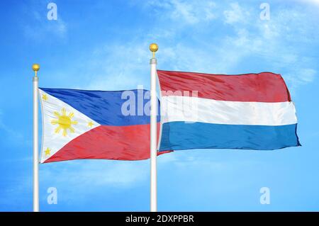 Philippines and Netherlands two flags on flagpoles and blue cloudy sky Stock Photo