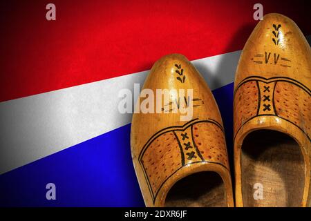 Closeup of a pair of wooden clogs made in Netherlands, on a Dutch Flag with copy space, top view. Stock Photo