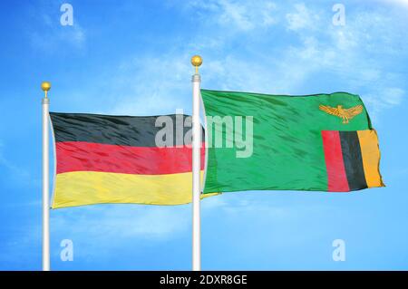 Germany and Zambia two flags on flagpoles and blue cloudy sky Stock Photo