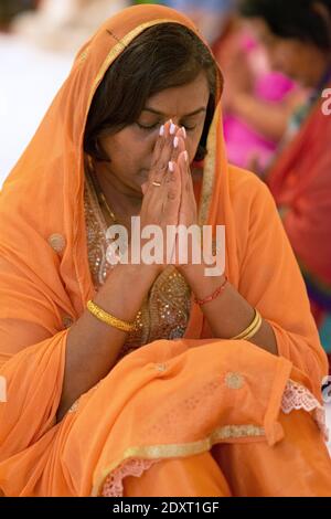 A devout Hindu worshipper prays and meditates iat a Sunday morning service inside a temple in South Richmond Hill, Queens, New York City. Stock Photo