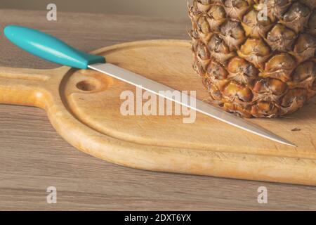 Close-Up of Pineapple and Knife on a wooden chopping board Stock Photo