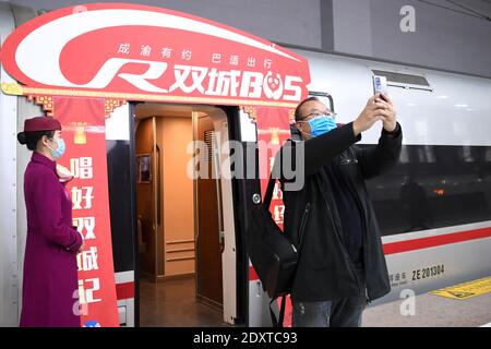 (201224) -- CHONGQING, Dec. 24, 2020 (Xinhua) -- A passenger takes a selfie before boarding the Fuxing high-speed train G8608 bound for Chengdu East Railway Station in southwest China's Sichuan Province, at Shapingba Railway Station in southwest China's Chongqing on Dec. 24, 2020. On Thursday morning, with G8608 and G8607 trains respectively pulling out of Chongqing Shapingba Railway Station and Chengdu East Railway Station, the Fuxing CR400AF trains plying on the railway linking Chengdu, capital of Sichuan Province, and Chongqing Municipality were officially put into operation at a speed of Stock Photo