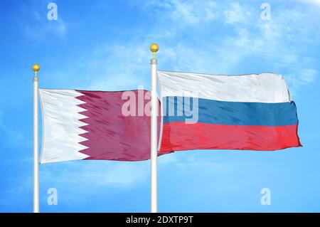 Qatar and Russia two flags on flagpoles and blue cloudy sky Stock Photo