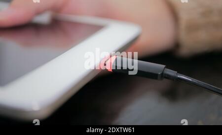 Woman's hand plugging black lightning charging cable into tablet Stock Photo