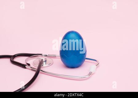 Stethoscope with classic blue egg on a pink background. copy space Stock Photo