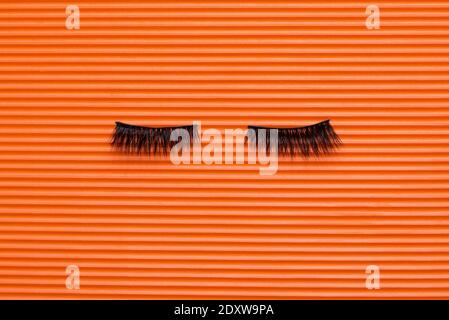 Black false lashes strips on orange textured background Stock Photo