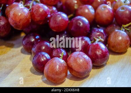 Close up view of a bunch of red grapes on a wooden chopping board. Stock Photo