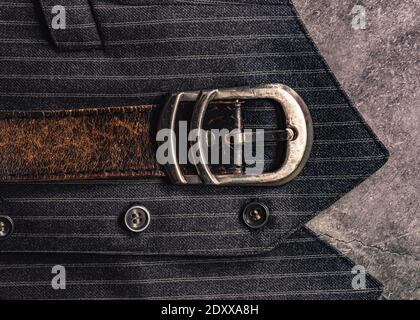 Close-up of a chrome belt buckle of a leather belt on a striped gray waistcoat Stock Photo