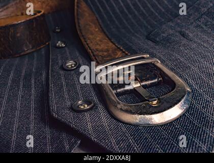 Close-up of a chrome belt buckle of a leather belt on a striped gray waistcoat Stock Photo