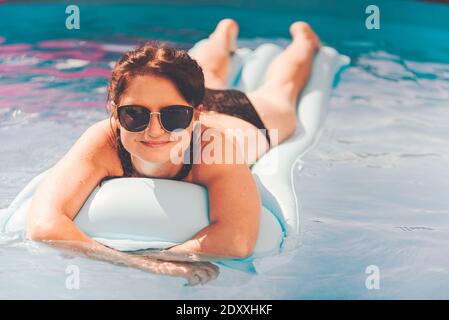 Young woman on pool air mattress in above ground pool. Stock Photo