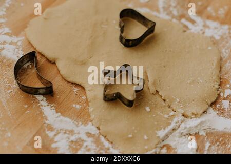 A closeup of the shaped cookie cutters on the dough on a wooden surface Stock Photo