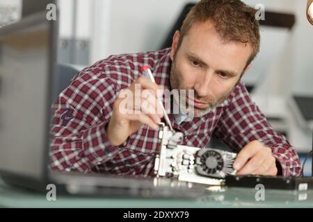 man is repairing broken pc with a screw driver Stock Photo