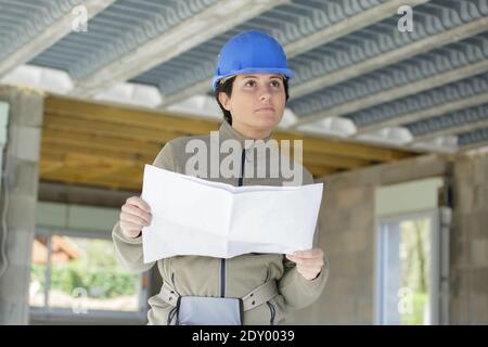 female builder holds plans and inspects property Stock Photo