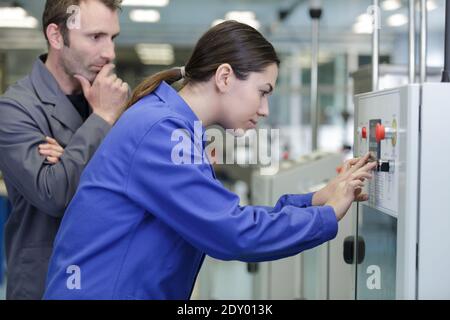 female apprentice working with engineer on cnc machinery Stock Photo