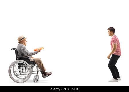 Full length profile shot of an elderly man in a wheelchair playing throwing a plastic disk with a young man isolated on white background Stock Photo