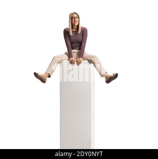 Cheeful young woman sitting on a white column bar isolated on white background Stock Photo