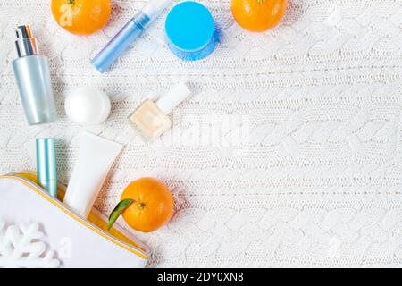 winter flat lay with cosmetics, snowflake and mandarins on white knitted background. Stock Photo