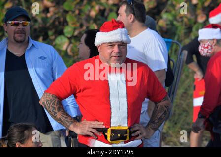 Indialantic, Brevard County, Florida, USA. December 24, 2020. The Christmas Eve Surfing Santa 2020 was a scaled down event this year due to Covid-19. A small group dressed in Christmas attire ventured into the choppy surf of the Atlantic Ocean as a few hundred spectators watched from the beach. Credit: Julian Leek/Alamy Live News Stock Photo