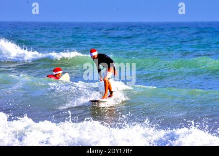 Indialantic, Brevard County, Florida, USA. December 24, 2020. The Christmas Eve Surfing Santa 2020 was a scaled down event this year due to Covid-19. A small group dressed in Christmas attire ventured into the choppy surf of the Atlantic Ocean as a few hundred spectators watched from the beach. Credit: Julian Leek/Alamy Live News Stock Photo