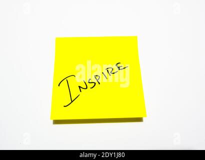 Inspire hand written note on a yellow sticky note with white background Stock Photo