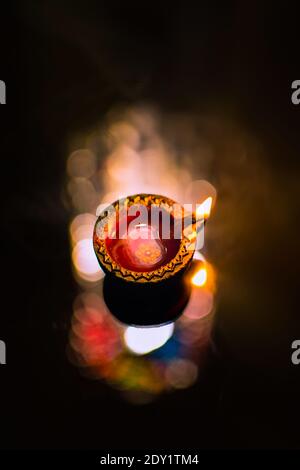 Earth diya lightened during the festival of lights Diwali the Hindu festival in India with shiny bokeh reflection background. Stock Photo