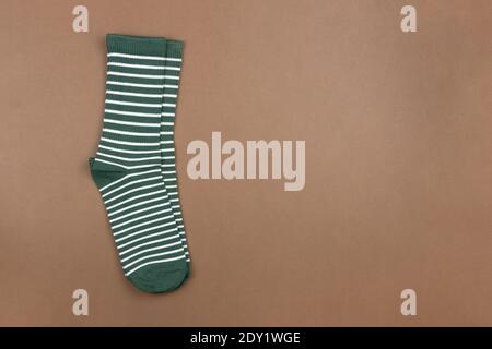 Pair of green striped socks on brown background, flatly, minimal style, top view, copy space. Concept male clothing, housekeeping, sorting, declutteri Stock Photo