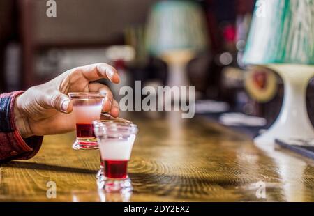 Drinking alcohol into shot glasses in a nightclub or bar. Man shots cocktail. Tequila shots, vodka,whisky, rum. Barman in pub. Tequila shot. Colorful Stock Photo