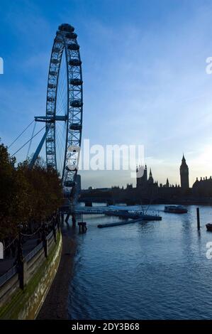 The Houses of Parliament and Big Beat sunset, seen behind the London Eye, a giant Ferris wheel on the South Bank of the Thames, London, England. Stock Photo