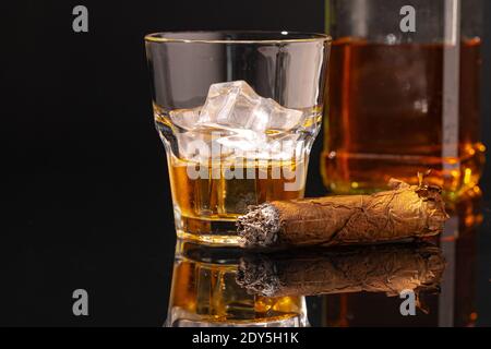 Glass of whisky and lighted cigar on black background Stock Photo