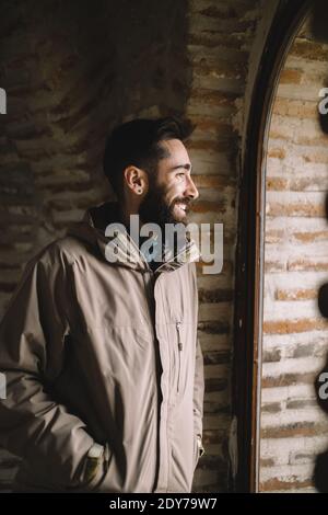 Smiling bearded man looking through the window Stock Photo
