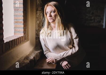 Young woman looking through a window Stock Photo