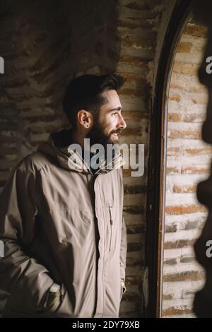 Smiling bearded man looking through the window Stock Photo