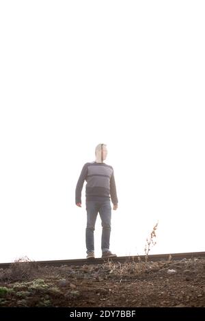 Man in dense fog standing on railway tracks while looking away Stock Photo