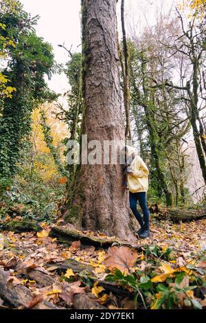 Young woman leaning against tree trunk Stock Photo