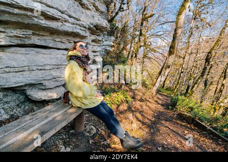Woman wearing yellow hood sitting on bench Stock Photo