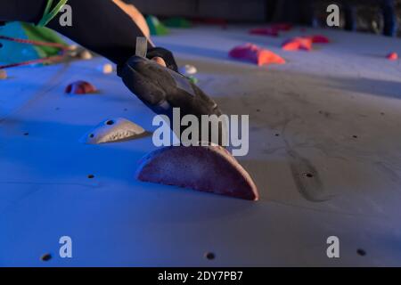 From below unrecognizable athlete stepping on grip while exercising on wall during climbing workout in gym Stock Photo
