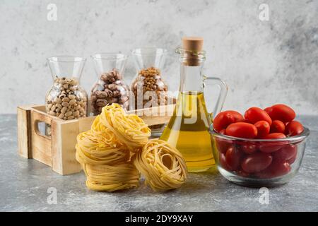 A bottle of oil with raw nest pasta and cherry tomatoes Stock Photo